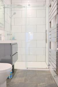 a white bathroom with a shower and a toilet at Delightful Dog Friendly Seaside Cottage in Shaldon Devon in Shaldon