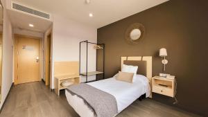 een slaapkamer met een bed en een spiegel aan de muur bij HOTEL MAUROS EL PUIG in El Puig