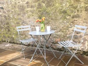 uma mesa com duas cadeiras e um vaso com flores em Delightful Dog Friendly Seaside Cottage in Shaldon Devon em Shaldon