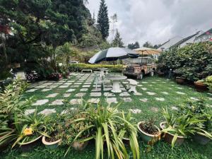 eine Terrasse mit einem Tisch, einem Sonnenschirm und Pflanzen in der Unterkunft Big Dreams Garden Stay in Tanah Rata