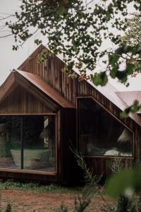 a wooden building with large windows in a field at Casa Friendly avec sa piscine chauffée … in Les Croix Chemins