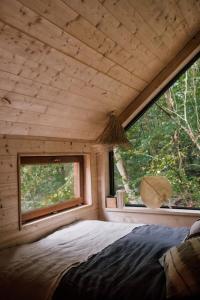 1 dormitorio en una cabaña de madera con una ventana grande en Casa Friendly avec sa piscine chauffée …, en Les Croix Chemins