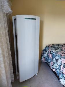 einen weißen Kühlschrank in einem Zimmer neben einem Bett in der Unterkunft Rancho Lux in Águas de Lindóia
