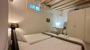 a white bedroom with two beds and a window at Fayrouz Psarrou Beach Mykonos in Mikonos
