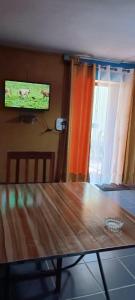 ein Wohnzimmer mit einem Holztisch und einem Flachbild-TV in der Unterkunft Studio Standard - AMI APPARTHOTEL in Tôlagnaro