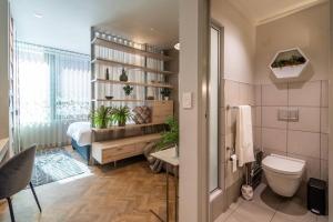 a bathroom with a toilet and a bed in a room at Vibrant Studio Apartment in Cape Town