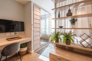 a living room with a television and plants in it at Vibrant Studio Apartment in Cape Town