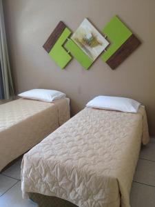 a room with two beds and pictures on the wall at Hotel Portal do Éden in Sorocaba