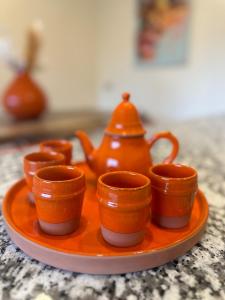 an orange plate with little cups and a teapot at Incantevole villa Safi Sidi Bouzid near beach in Safi