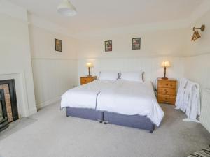 a white bedroom with a bed and two night stands at High Auchenbrack in Thornhill