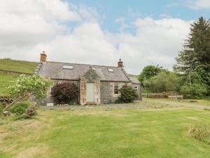 an old stone cottage with a grass yard at Prince's Cottage in Thornhill