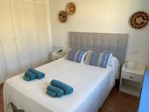 ein Schlafzimmer mit einem weißen Bett und blauen Handtüchern darauf in der Unterkunft Discover perfect beach Apartment, only 300m away in Vera