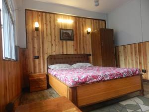 1 dormitorio con 1 cama y pared de madera en Dik's Home en Darjeeling