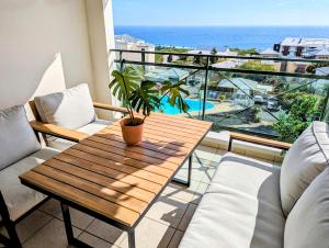 d'un balcon avec une table en bois et une vue sur l'océan. dans l'établissement Sunset Océan - appartement T2 avec vue imprenable sur l'océan et piscine, à Saint-Gilles les Bains