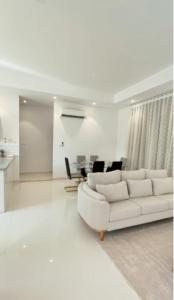 a white living room with a white couch and a table at Hawana VIP Private Apartment in Wādī Khasbar