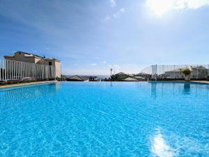 a large swimming pool with blue water at Sunset Océan - appartement T2 avec vue imprenable sur l'océan et piscine in Saint-Gilles-les-Bains