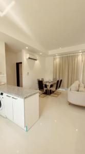 a white living room with a kitchen and a table at Hawana VIP Private Apartment in Wādī Khasbar