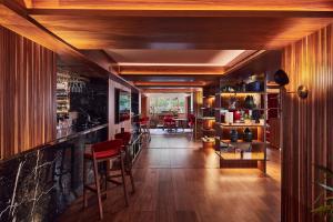 a long hallway with a bar with red chairs at The Level at Melia White House in London