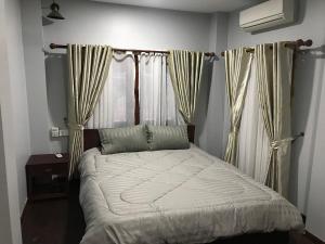 un letto in una camera da letto con tende e finestra di Apsara Khmer House a Siem Reap