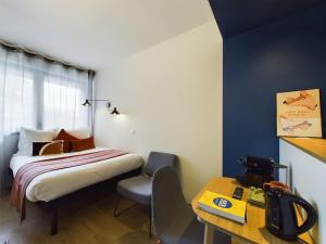 una camera d'albergo con letto, tavolo e scrivania di Hife Paris Gentilly a Gentilly