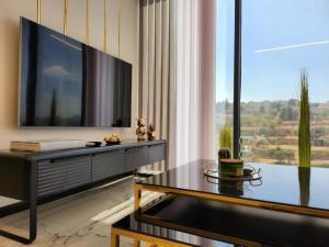 3BR Luxury Suite in Jerusalem في القدس: غرفة معيشة فيها تلفزيون كبير وطاولة