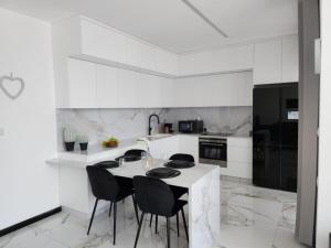 3BR Luxury Suite in Jerusalem في القدس: مطبخ أبيض مع طاولة وكراسي سوداء