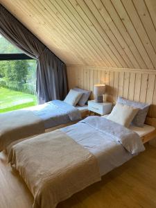 two beds in a room with a window at Love Wysove in Wysowa-Zdrój