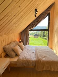 een slaapkamer met een bed en een groot raam bij Love Wysove in Wysowa-Zdrój