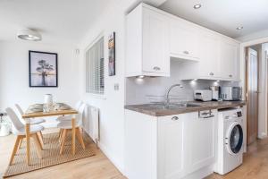 a kitchen with white cabinets and a table and a sink at Beta House by Night Stay: Contractors Sleeps 9 in Birmingham