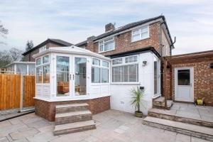 a house with a white conservatory on a patio at Beta House by Night Stay: Contractors Sleeps 9 in Birmingham