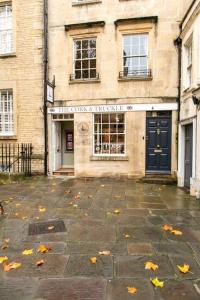 a building with a door and autumn leaves on the ground at Next to Bath Abbey & Roman Baths - Gorgeous Georgian House in Bath