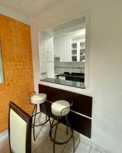 eine Küche mit zwei Hockern und einem Wandspiegel in der Unterkunft Apartamento Gorja in Praia Grande
