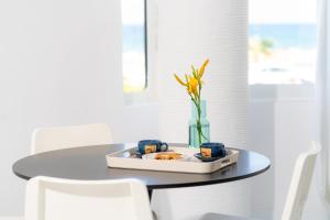 einen Tisch mit einem Teller Essen und einer Vase darauf in der Unterkunft SyntheSeas Residence in Rethymno
