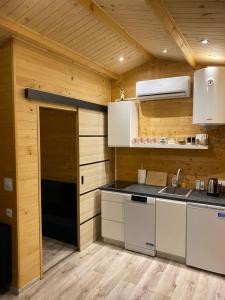 a kitchen with wooden walls and a door into a room at Domek pod gwiazdami z jacuzzi in Brzozowa