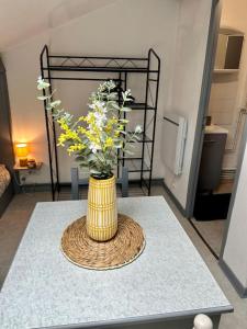a yellow vase with flowers in it on a table at Studio proche Gare in Bourg-en-Bresse