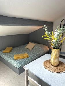 a bedroom with a bed and a table with a vase of flowers at Studio proche Gare in Bourg-en-Bresse
