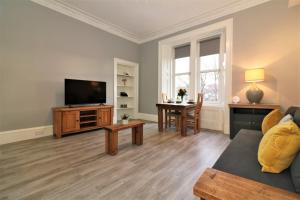 a living room with a couch and a tv and a table at Signature - Linden House Flat 4 in Airdrie