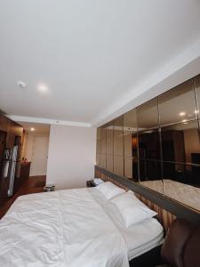 een slaapkamer met een groot wit bed en spiegels bij Beststay @Mataramcity yudhistira tower in Kejayan
