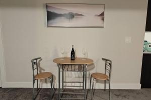 BlissfulAbode Basement Suite في إيرداري: طاولة مع ثلاثة كراسي وزجاجة من النبيذ