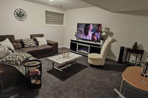 a living room with a couch and a flat screen tv at BlissfulAbode Basement Suite in Airdrie