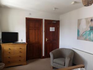 Zimmer mit einer Kommode, einem TV und einem Stuhl in der Unterkunft Red Lion Hotel in Ystrad Meurig