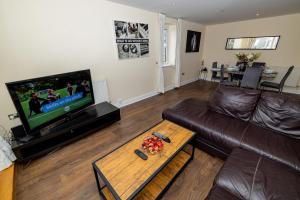 a living room with a brown leather couch and a tv at Nice Room Close to City231 in London