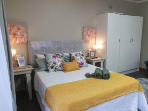 a bedroom with a large bed with a yellow blanket at Tree Orchid in Polokwane