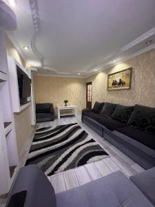 a living room with a black couch and a rug at 15 Apartments in Shymkent