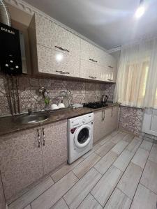 eine Küche mit einer Waschmaschine und einem Waschbecken in der Unterkunft 15 Apartments in Schymkent