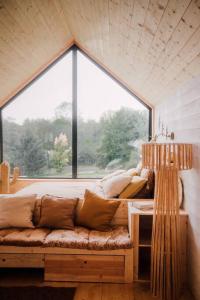 Sofá en habitación con ventana grande en Casa Moon & son bain nordique sur le lac en Les Croix Chemins