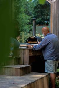 Een man stopt iets in een oven. bij Casa Moon & son bain nordique sur le lac in Les Croix Chemins