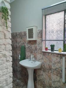 a bathroom with a sink and a stone wall at Tree Orchid in Polokwane