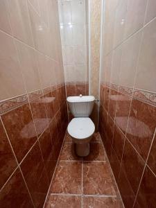 a bathroom with a toilet in a tiled room at Апартаменты на Mege in Shymkent