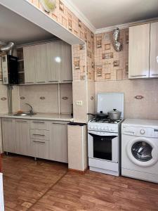 a kitchen with a stove and a washing machine at Апартаменты на Mege in Shymkent